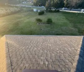 New ridge installation and Weathered Wood architectural shingles shown across upper roof plane after full replacement in Mount Dora, FL. Upper slope showing crisp new ridge line