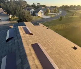 Two newly installed brown off-ridge vents integrated into the completed Weathered Wood roof system in Mount Dora, FL. Completed roof with two off-ridge vents installed