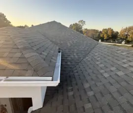 Long ridge line view displaying uniform shingle spacing and complete Weathered Wood system installation after storm damage repair. Long ridge line view showcasing uniform shingle layout