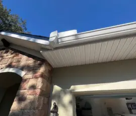 Clean roofline showing new shingles, white soffit, and newly installed gutters after major hail damage repair in DeLand. Clean roofline showing new shingles, white soffit, and newly installed gutters after major hail damage repair in DeLand.